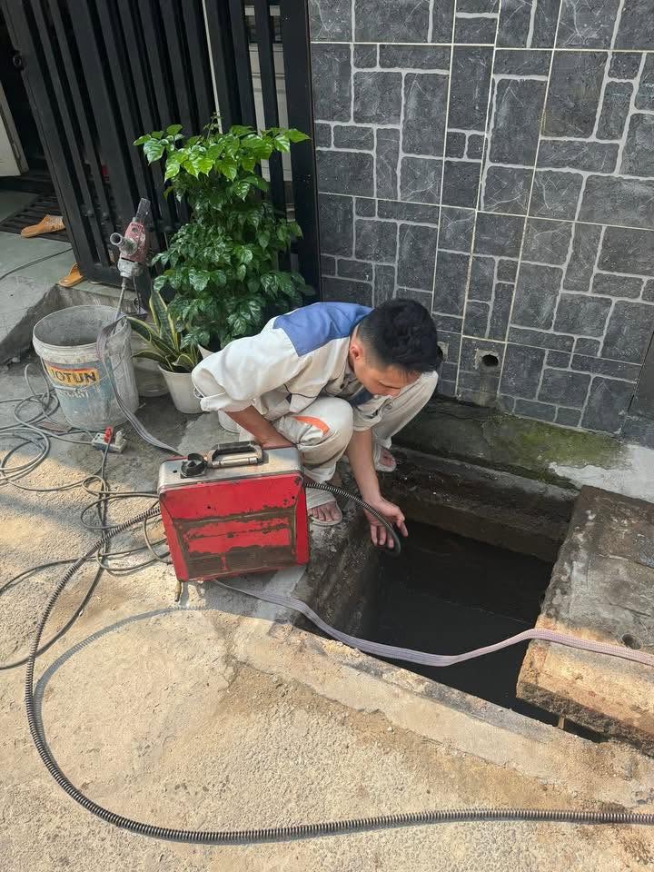 Kỹ thuật viên Môi Trường Xanh Đà Nẵng đang xử lý thông tắc cống nghẹt bằng máy lò xo chuyên dụng tại công trình thực tế.