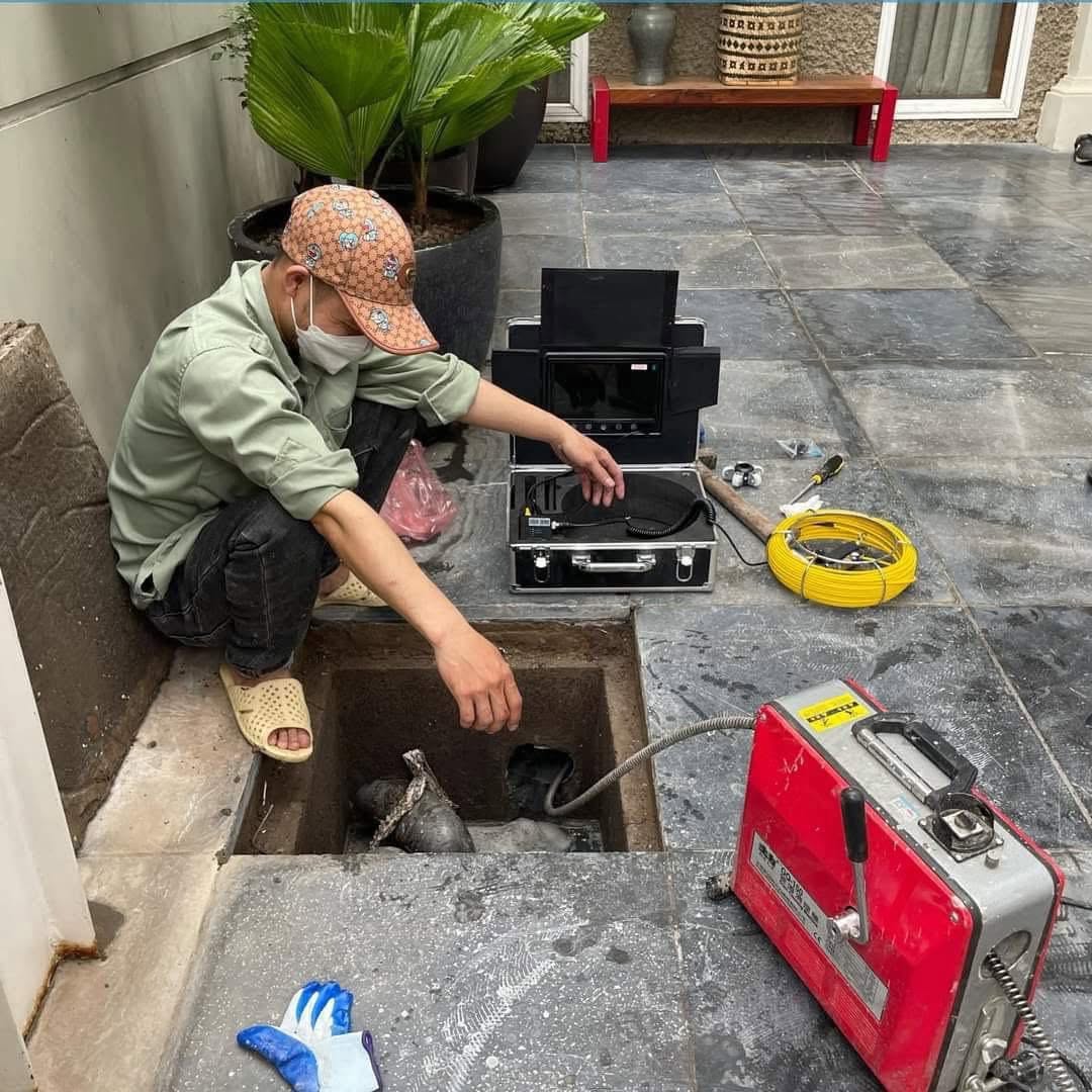 Kỹ thuật viên Môi Trường Xanh Đà Nẵng đang sử dụng máy lò xo chuyên dụng để xử lý thông tắc cống nghẹt tại nhà dân.